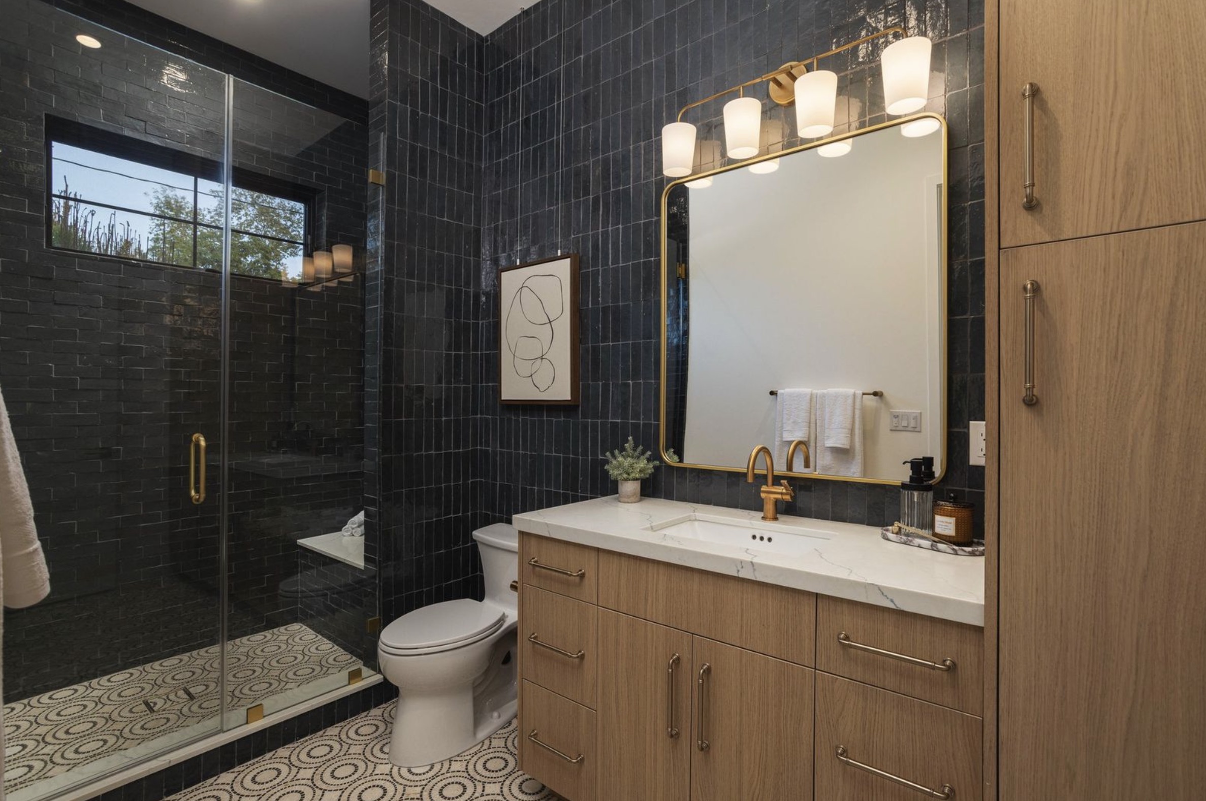 Westminster residence bathroom with black tile, oak vanity, brass fixtures, and patterned floor