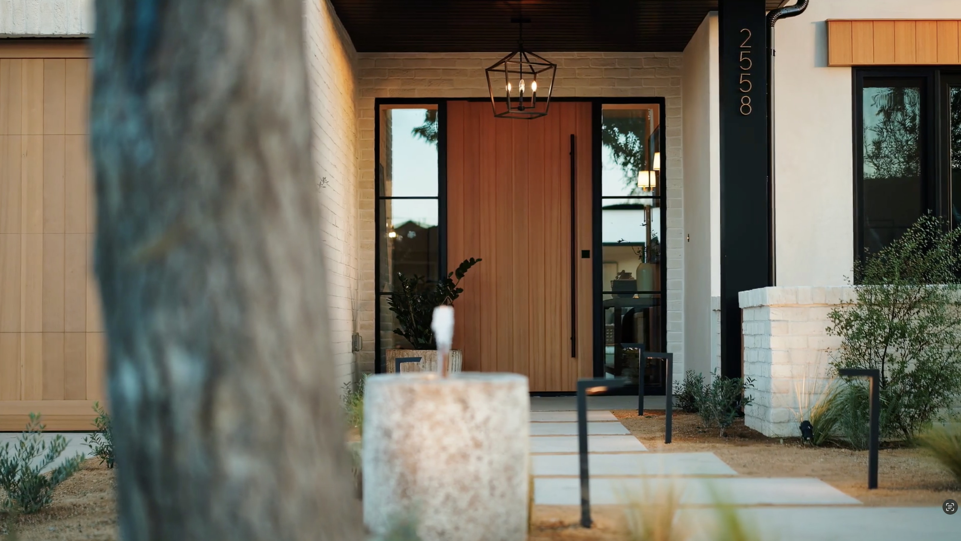 Westminster residence entry with warm wood door, white brick, black steel windows, and modern landscaping