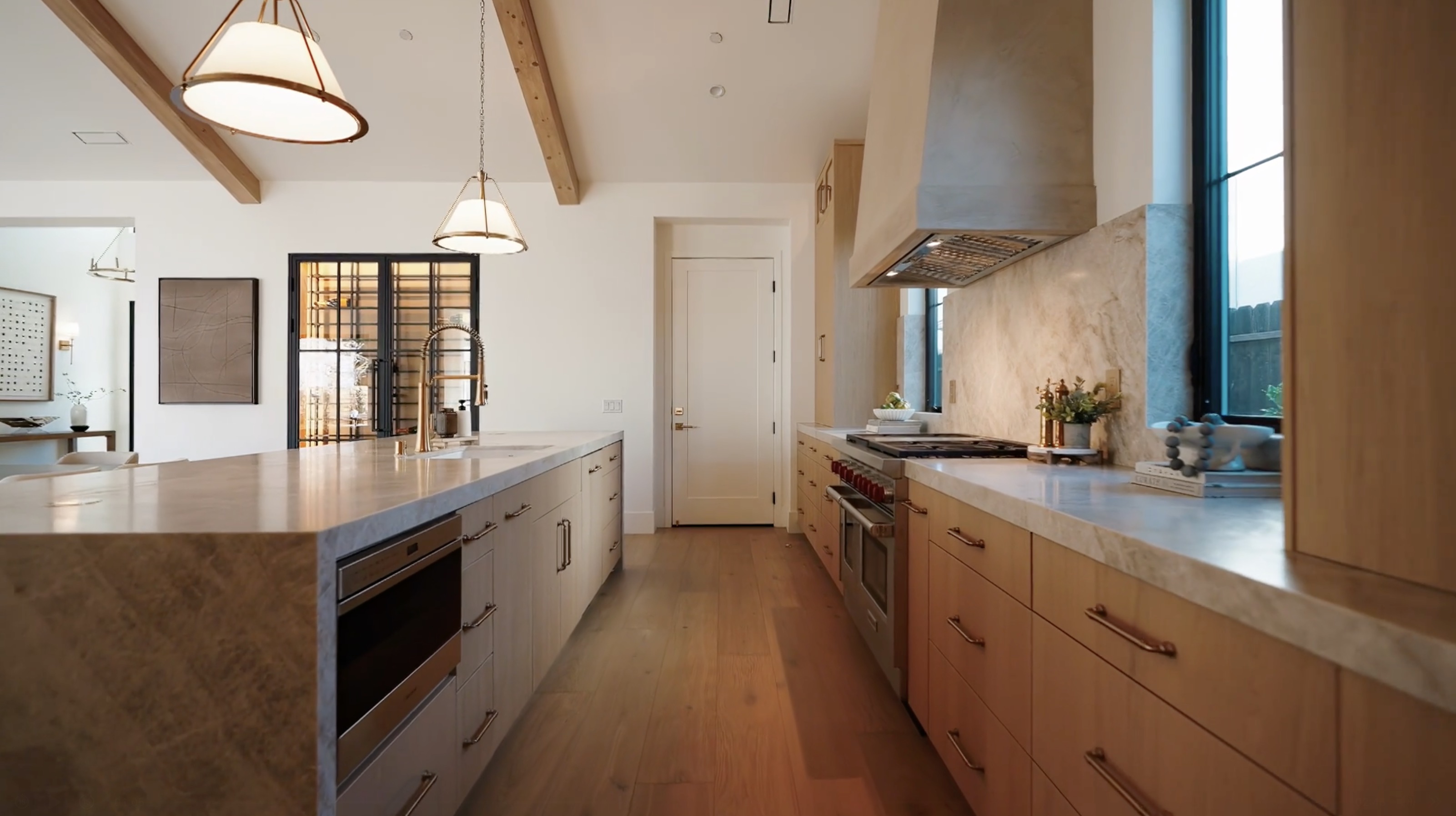 Westminster residence kitchen with stone island, oak cabinets, range, brass fixtures, and exposed beams